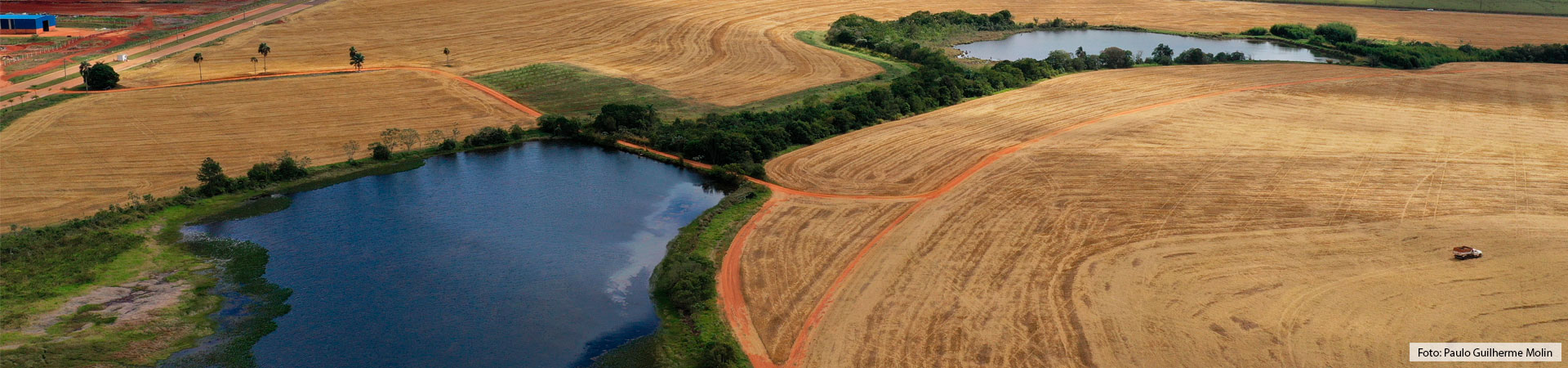 Imagem aérea onde visualiza-se 2 açudes e parte das plantações de trigo, as quais estão em processo de colheita